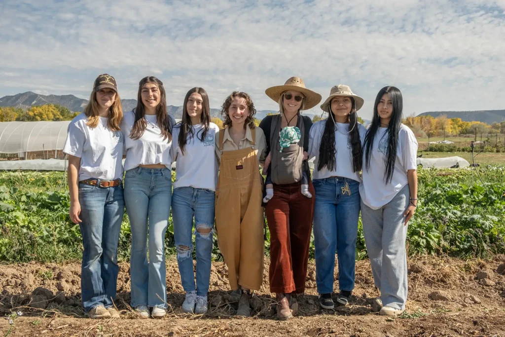 A group of young women stand in a crop field